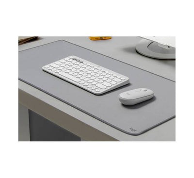 Ergonomic low-profile Pebble Mouse 2 being used next to a tablet on a clean, minimalist workstation setup.