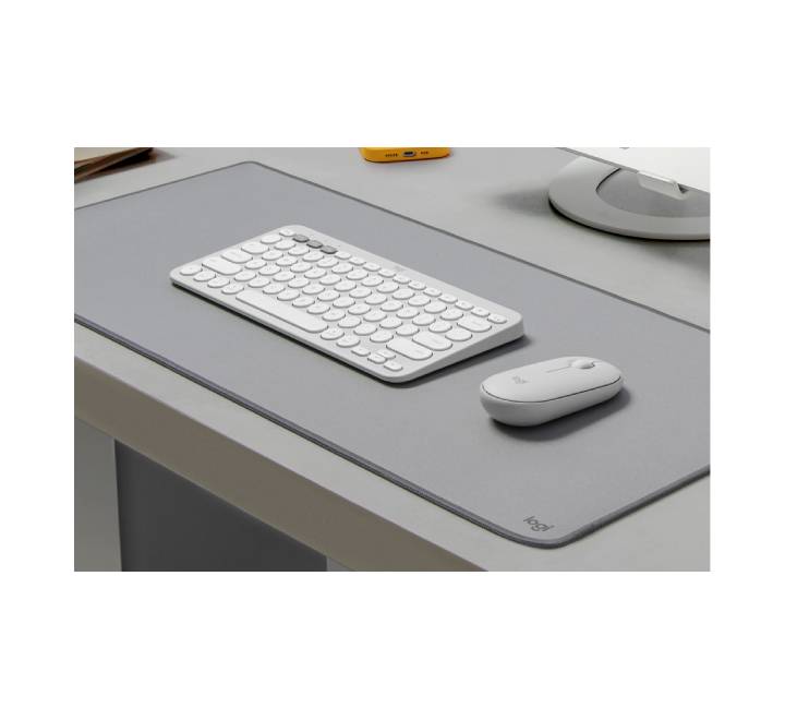 Ergonomic low-profile Pebble Mouse 2 being used next to a tablet on a clean, minimalist workstation setup.